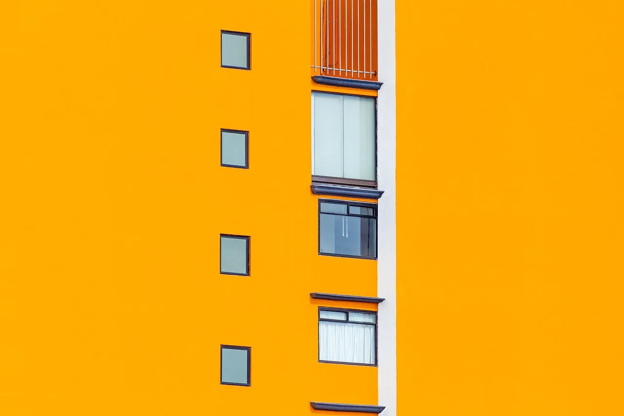 Façade orange d'un immeuble moderne percée de petites fenêtres carrées